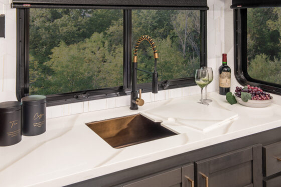 Interior view of the 2025 Heartland RV Bighorn 391MFB Fifth Wheel kitchen showing the kitchen sink with a half-open cabinet below.