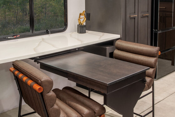 Interior of the 2025 Heartland RV Bighorn 391MFB Fifth Wheel, showcasing a kitchen with a swing-out desk.