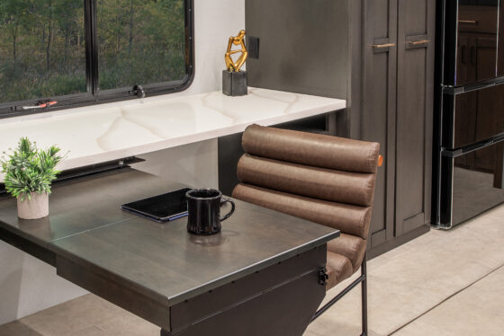 Interior view of the 2025 Heartland RV Bighorn 391MFB Fifth Wheel, featuring a kitchen with a swing-out desk and cabinetry.