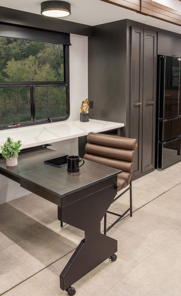 Interior view of the 2025 Heartland RV Bighorn 391MFB Fifth Wheel, featuring a kitchen with a swing-out desk and cabinetry.