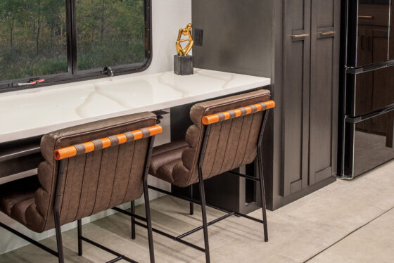 Interior of the 2025 Heartland RV Bighorn 391MFB Fifth Wheel kitchen featuring a swing-out desk and cabinetry.