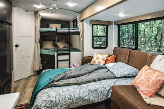 A cozy bedroom inside a Heartland RV, featuring a comfortable bed and soft lighting.