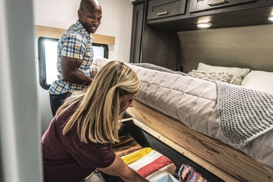 A cozy bedroom inside a Heartland RV, featuring a comfortable bed and warm lighting.