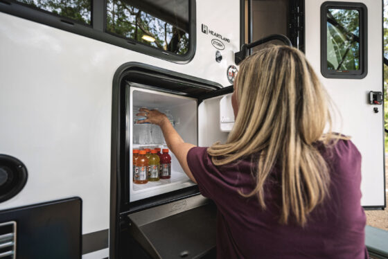 Exterior view of a travel trailer with a built-in fridge mounted into the side.