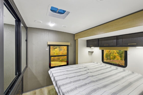 A cozy bedroom inside a Heartland RV, featuring a comfortable bed and warm lighting.