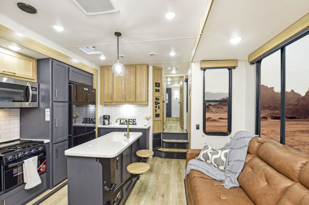 Interior of the 2024 Heartland Torque TQ418 Toy Hauler, showcasing the kitchen and living area with modern cabinetry, stainless steel appliances, and ample seating.