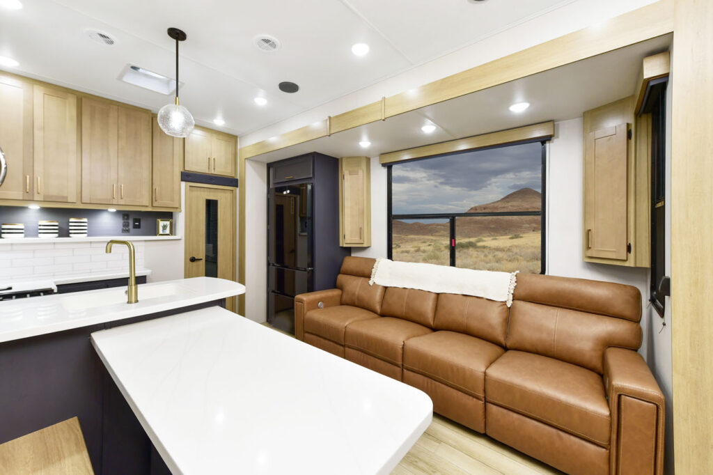 Interior of the 2024 Heartland Torque fifth wheel RV, featuring a cozy couch, modern kitchen, and large windows offering plenty of natural light.