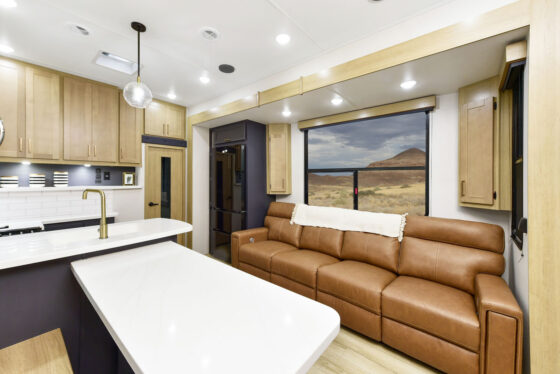 Interior of the 2024 Heartland Torque fifth wheel RV, featuring a cozy couch, modern kitchen, and large windows offering plenty of natural light.