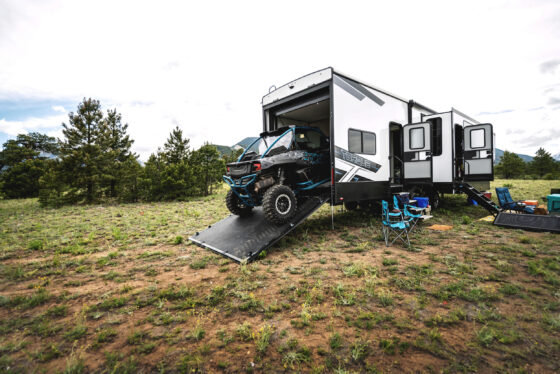 ATV driving up a ramp into the garage of a Heartland Torque RV, demonstrating its versatile storage space.