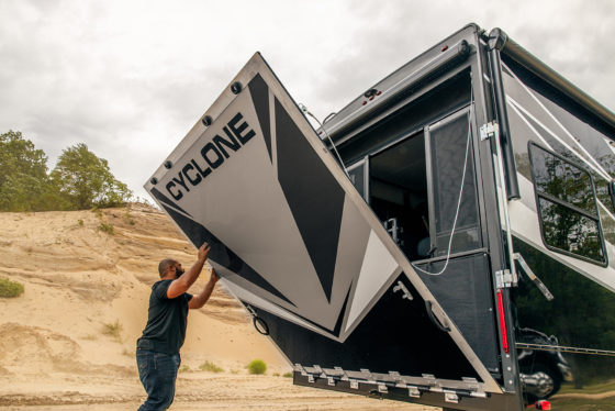 Rear exterior view of the 2025 Heartland Cyclone Fifth Wheel with the toy hauler ramp door closing, highlighting the rugged design and durable structure.