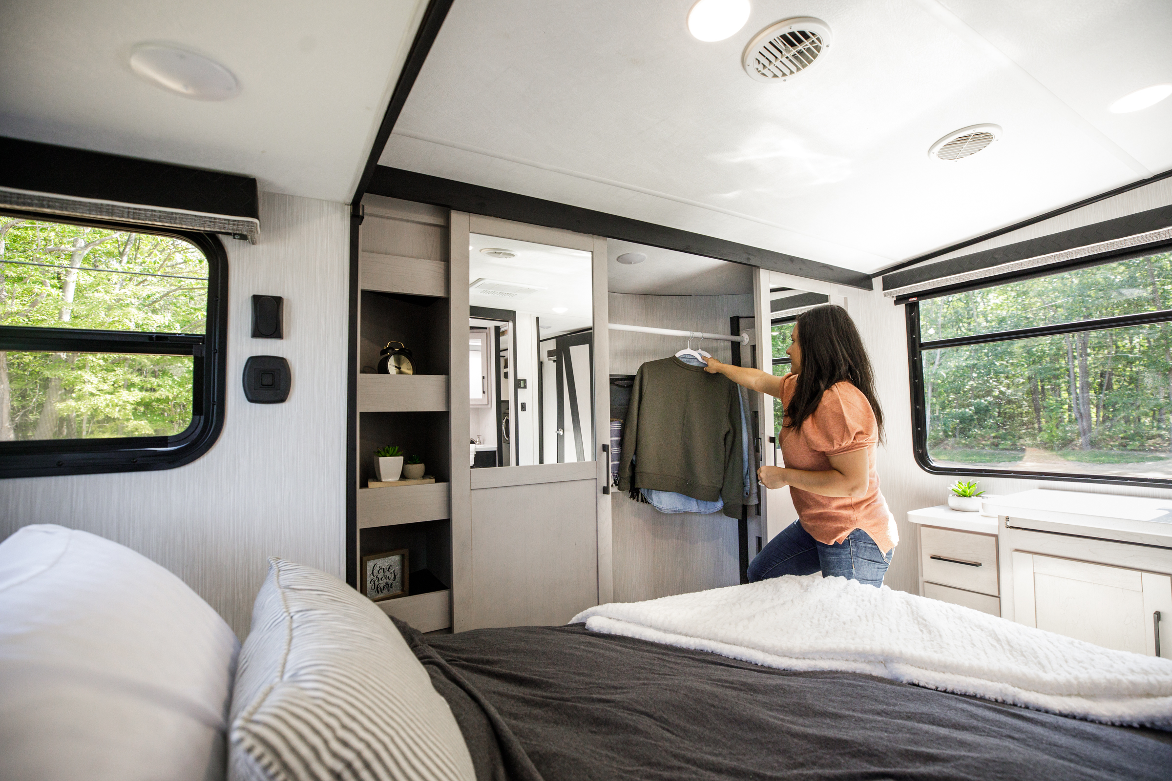 A woman hanging up clothes in the spacious Cyclone RV bedroom.