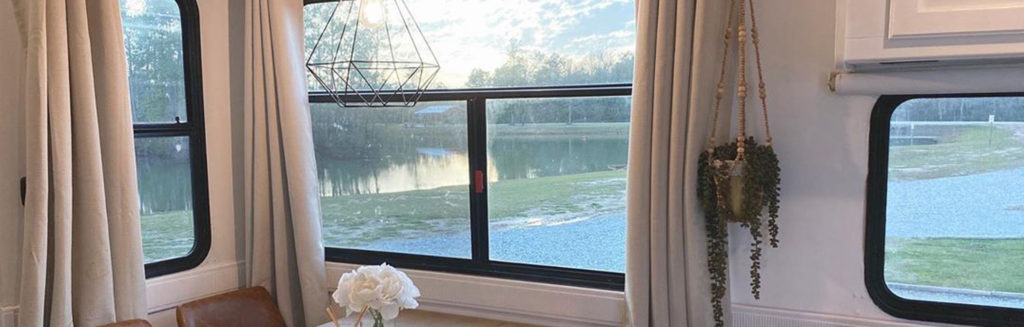 Window to the World: A view from inside an RV, looking out onto still waters and a green landscape.