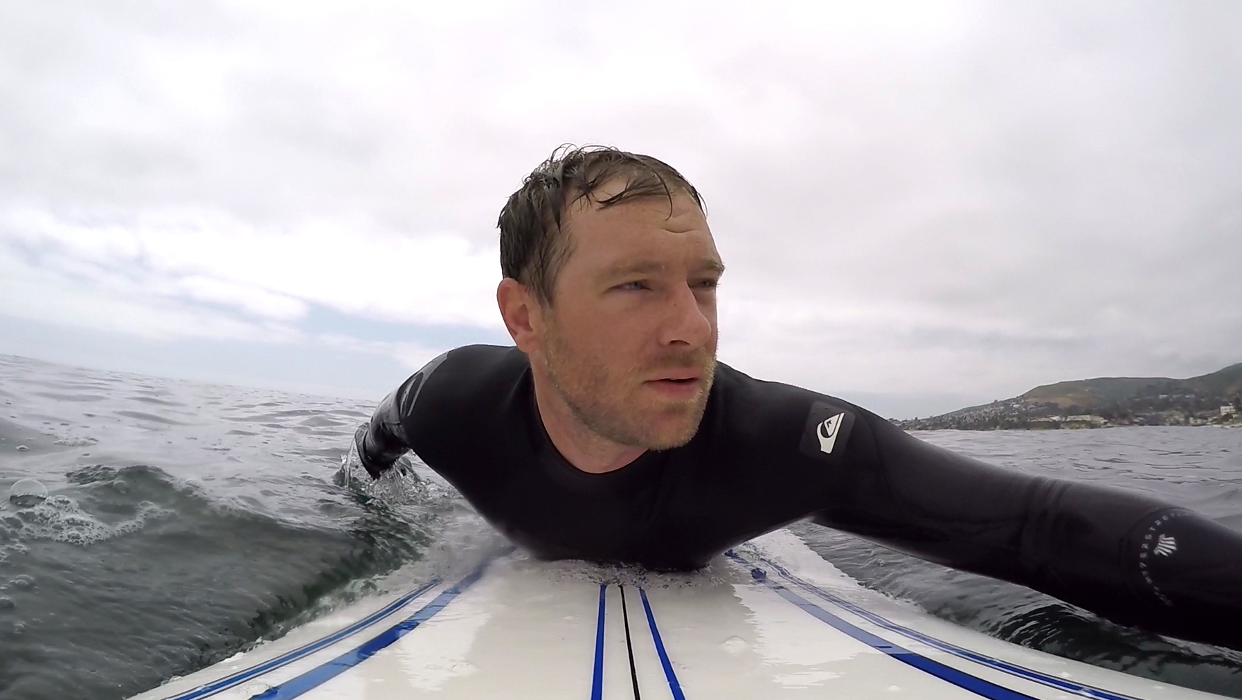 A close up shot of Eric's face as he paddles on a surf board.