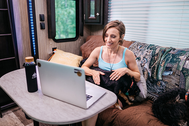 A woman holding a dog on her lap as she has a video call on her computer.