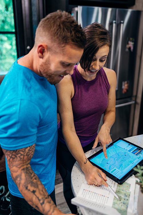 A man and a woman planning their travel route on a tablet.