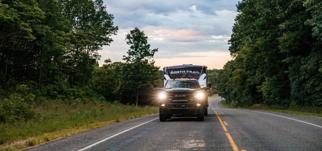 A North Trail travel trailer towed by a truck on the road.