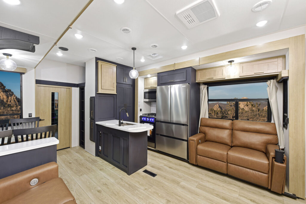 Interior of the 2024 Heartland Cyclone 4014C, featuring a cozy seating area and a fully equipped kitchen with modern appliances.