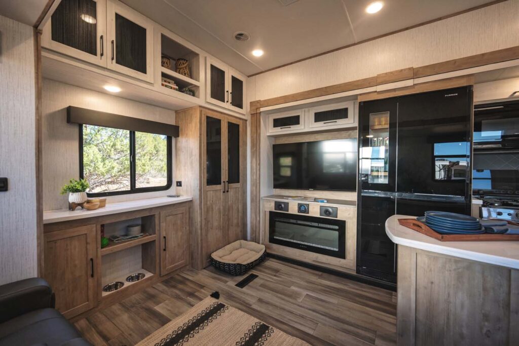 Kitchen area inside the 2025 Heartland RV Bighorn 391MFB Fifth Wheel, featuring a refrigerator, oven, and built-in storage.
