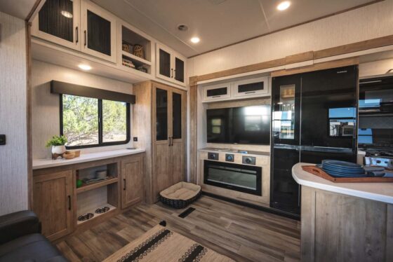 Kitchen area inside the 2025 Heartland RV Bighorn 391MFB Fifth Wheel, featuring a refrigerator, oven, and built-in storage.