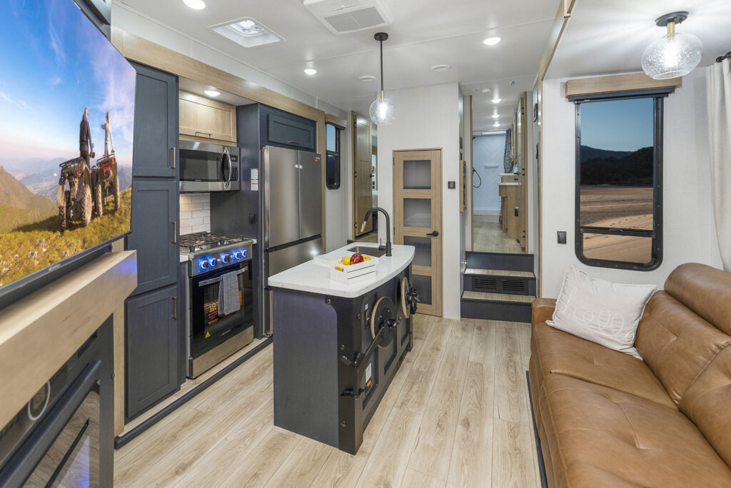 Interior view of the 2024 Heartland Cyclone 4118, showcasing the spacious living area with theater seating, a sofa, entertainment center, and a fully equipped kitchen.