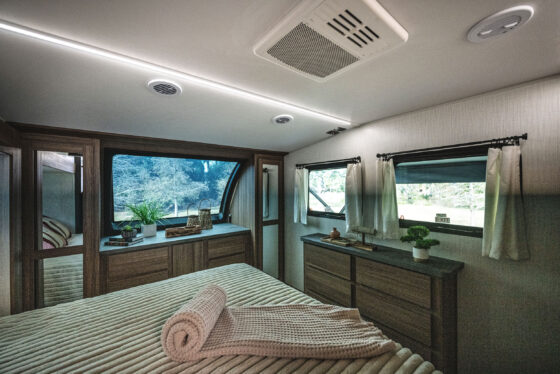Interior view of the bedroom in the 2024 Heartland Corterra fifth-wheel RV, featuring a large bed, stylish furnishings, and ample storage space.