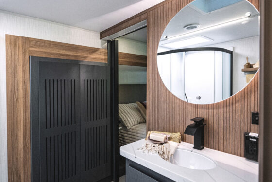 Close-up of the bathroom vanity in the 2024 Heartland Corterra fifth-wheel RV, showcasing a sleek design with modern fixtures, a large mirror, and ample counter space.