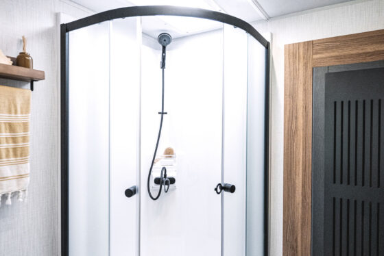 Interior view of the shower in the 2024 Heartland Corterra fifth-wheel RV, showcasing a spacious design with a sliding door, modern fixtures, and stylish tiles.