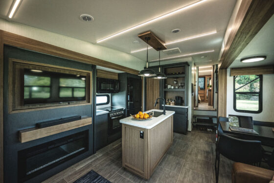 Interior view of the 2024 Heartland Corterra fifth-wheel RV kitchen, featuring a spacious island, modern appliances, and sleek cabinetry.
