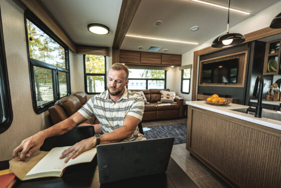 Interior view of the dining table and living room in the 2024 Heartland Corterra fifth-wheel RV, featuring stylish seating, a modern dining area, and spacious layout.