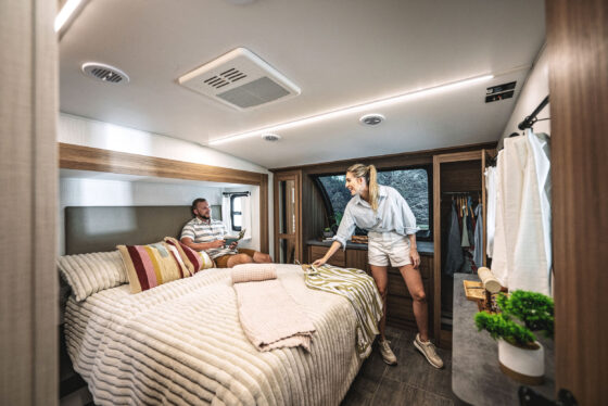 Interior view of the bedroom in the 2024 Heartland Corterra fifth-wheel RV, featuring a quuen-size bed, modern furnishings, and ample storage space.