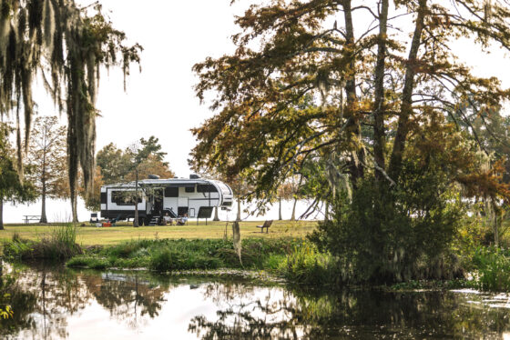 Side view of the 2024 Heartland Corterra fifth-wheel RV parked outdoors, showcasing its sleek design, large slide-outs, and bold exterior graphics.