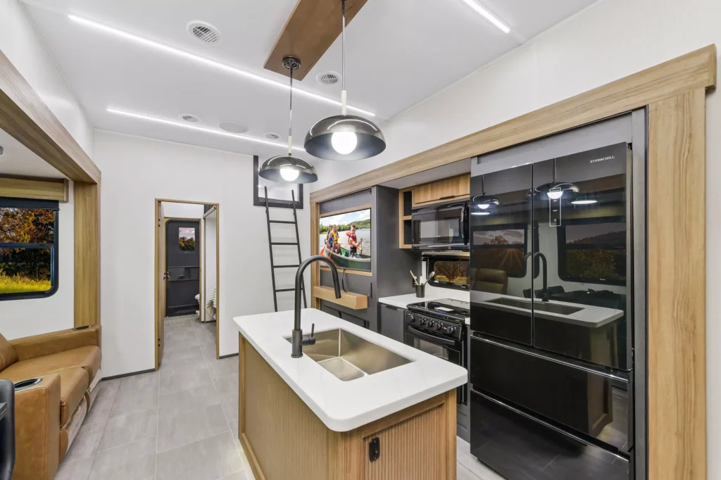 Interior view of the kitchen in the 2024 Heartland Corterra fifth-wheel RV, showcasing modern appliances, countertops, and ample storage space.