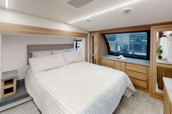 Bedroom interior of the 2024 Heartland Corterra fifth-wheel RV, featuring a large bed, stylish decor, and ample storage.