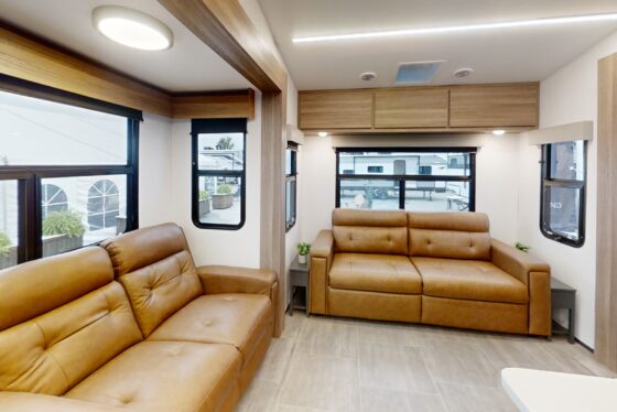 Living room interior of the 2024 Heartland Corterra CT30 fifth-wheel RV, featuring plush seating, large windows, and a stylish entertainment area.