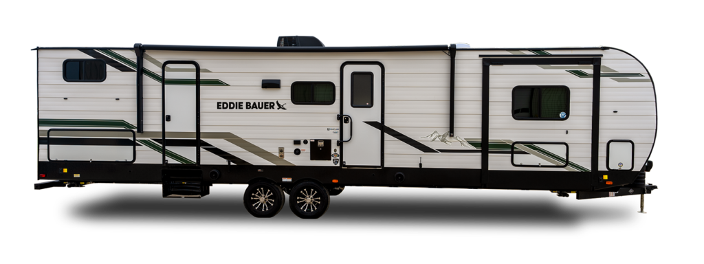 A white Eddie Bauer travel trailer with green and black stripes, two axles, multiple windows, and a door near the front. The trailer has outdoor utility connections and mountain graphics on its side.