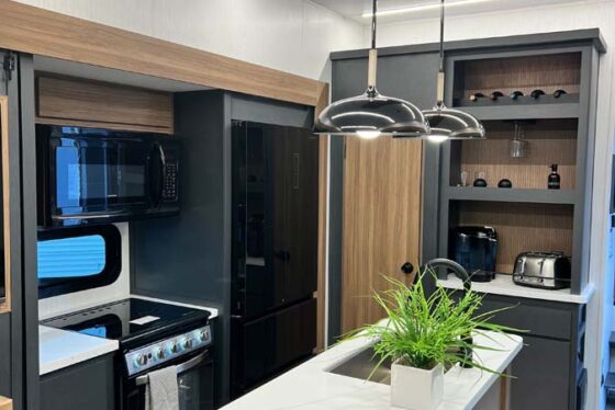 Interior view of the kitchen in the Heartland Corterra fifth-wheel RV, featuring modern appliances, ample cabinetry, and a sleek countertop.