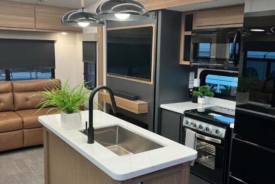 Interior view of the kitchen in the Heartland Corterra fifth-wheel RV, featuring modern appliances, countertops, and cabinetry.