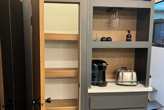 Interior view of the Heartland Corterra fifth-wheel RV, focusing on the kitchen with modern appliances, countertops, and cabinetry.