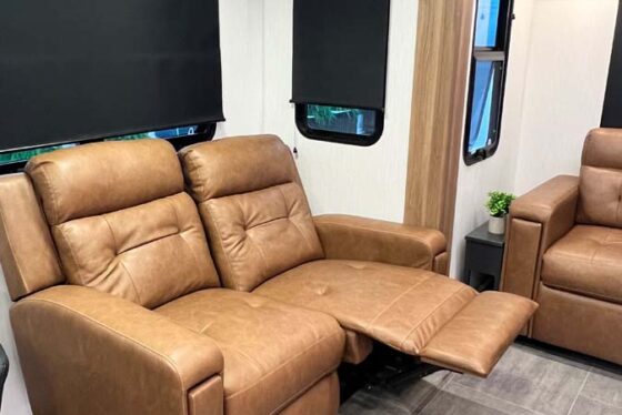 Interior of the Heartland Corterra fifth-wheel RV showing a spacious living area with comfortable seating, large windows, and stylish decor.
