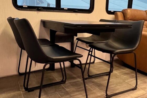 Interior view of the dining area in the Heartland Corterra fifth-wheel RV, featuring a stylish dining table with seating.