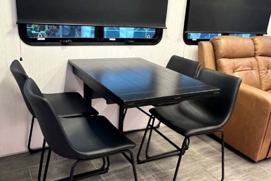 Interior view of the dining area in the Heartland Corterra fifth-wheel RV, featuring a stylish dining table with seating.