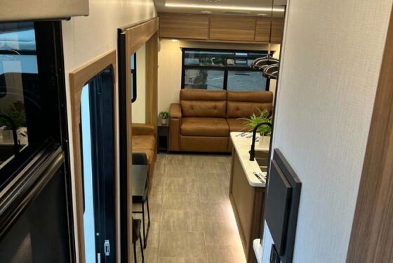 Interior view of the Heartland Corterra fifth-wheel RV, showcasing the kitchen area and comfortable seating with stylish cushions and modern design.