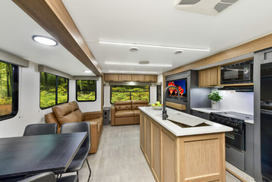 Interior of the 2024 Heartland Cyclone 4008 Fifth Wheel Toy Hauler, showcasing the open kitchen and living area with modern appliances, cozy seating, and stylish décor.