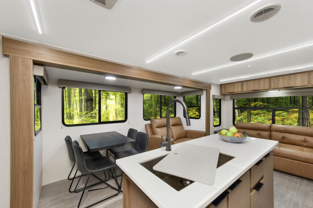 Interior of the 2024 Heartland Cyclone CT 30.3RL Fifth Wheel Toy Hauler, featuring a modern kitchen with appliances and a cozy seating area with plush sofas.
