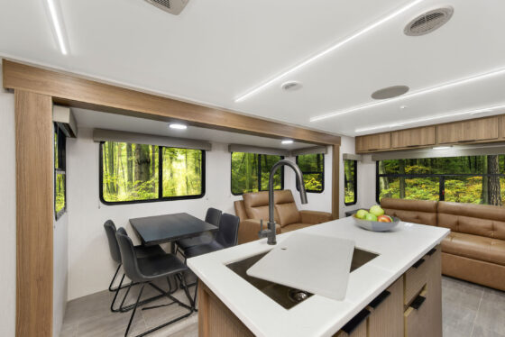 Interior of the 2024 Heartland Cyclone CT 30.3RL Fifth Wheel Toy Hauler, featuring a modern kitchen with appliances and a cozy seating area with plush sofas.