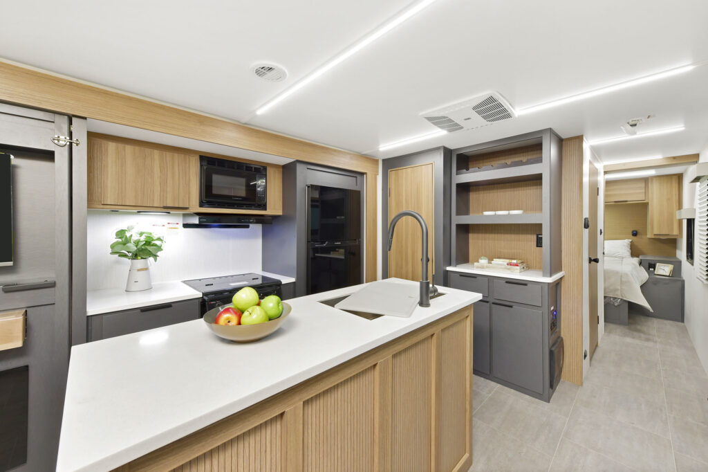 Interior view of the kitchen in the 2024 Heartland Compass 30.3RL motorhome, featuring modern appliances, spacious countertops, and sleek cabinetry.