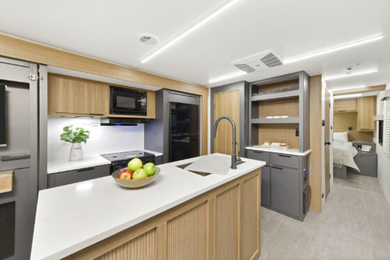Interior view of the kitchen in the 2024 Heartland Compass 30.3RL motorhome, featuring modern appliances, spacious countertops, and sleek cabinetry.