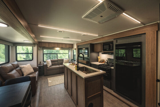 Alt Text: Interior of the 2024 Heartland Cyclone 4008 Fifth Wheel Toy Hauler, featuring a comfortable seating area with plush chairs and large windows for natural light.