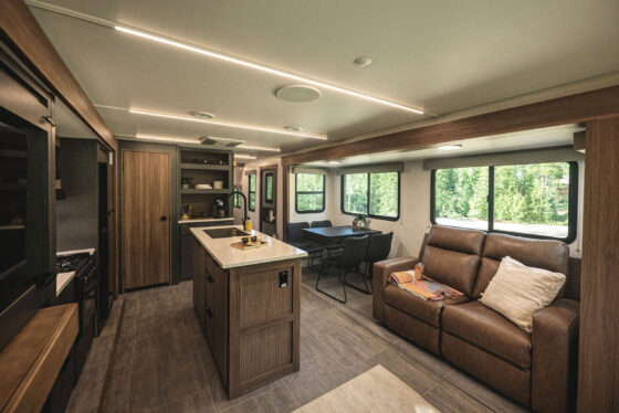 Interior of the 2024 Heartland Cyclone 4008 Fifth Wheel Toy Hauler, showing the kitchen and living room area with modern appliances, comfortable seating, and stylish décor.