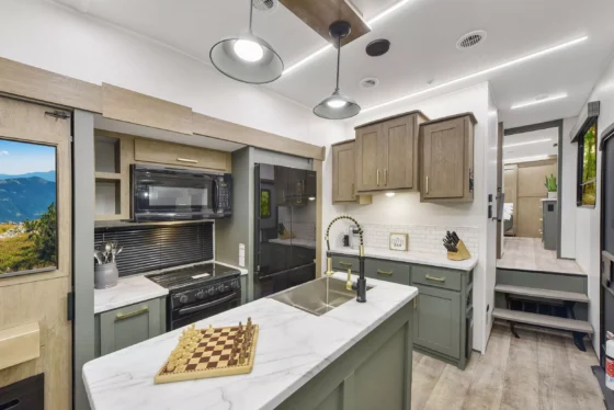Modern kitchen inside the 2024 Heartland Eddie Bauer 3100RL Fifth Wheel, featuring a spacious island, stainless steel appliances, and stylish cabinetry.